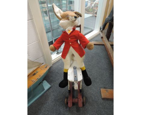 A vintage Merrythough made for Harrods soft toy modelled as a standing fox in hunting attire on a wooden push along horse