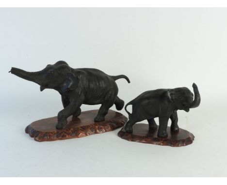 A Meiji period bronze of a running elephant, character mark to the underside on carved wooden base, 30cm long, together with 