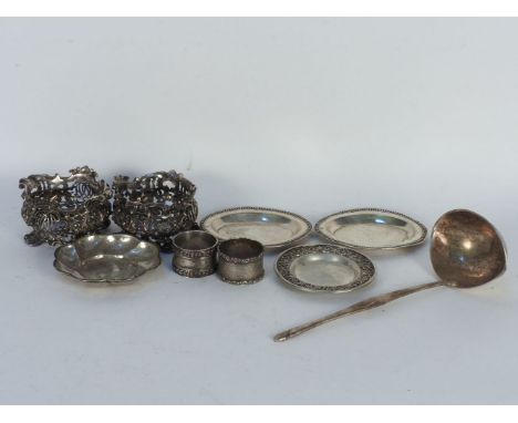 Four various continental white metal pin dishes, a white metal sauce ladle, two sterling silver napkin rings and a silver bac