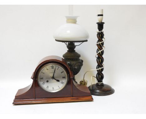 An oil lamp, a mantel clock by Camerer Cuss, and a wooden table lamp