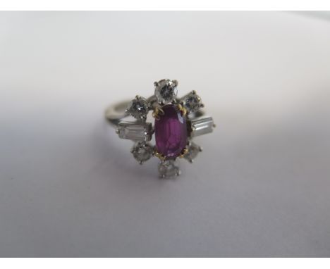 An 18ct white gold ruby and diamond cluster ring, the centre ruby approx 1.5ct, surrounded by 2 baguette cut diamonds and six