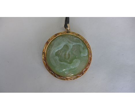 A carved jade pendant in a 14ct yellow gold mount - 5.5cm wide - in good condition 