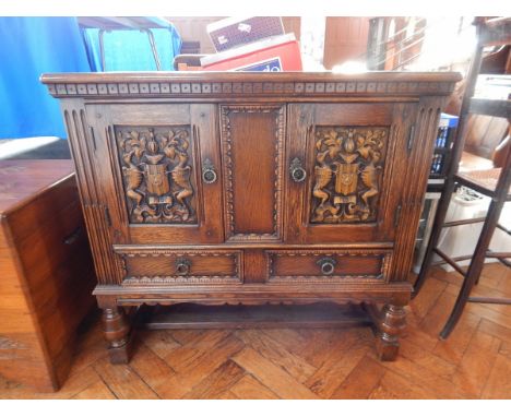 An oak Victorian side cabinet with coat of arms, on cup and ball and block feet, 91cm wide 