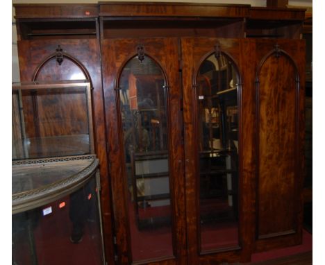 An early Victorian mahogany four door breakfront wardrobe, having twin central arched mirror doors enclosing fitted linen sli