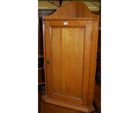An early 20th century light oak hanging single door corner cupboard