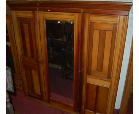 *An Aesthetic Movement walnut triple wardrobe, the central mirror door flanked by twin recess panelled doors, width 205cm