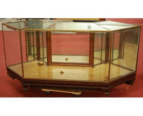 An early 20th century mahogany and brass bound corner shop display cabinet having single mirrored rear door, flanked by furth