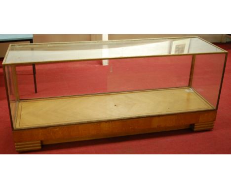 An Art Deco light oak and brass bound shop display cabinet of good size, having single glazed rear sliding door (other door m