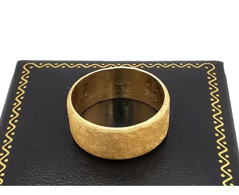 An 18ct yellow gold wide textured band. Inscribed to the interior Robin and a date. Stamped 18K,750. Ring size K. Weight 5.62