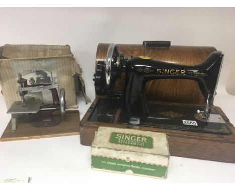 A Singer sewing machine in an oak case as new a small childs sewing machine and a boxed Singer buttonhole attachment together