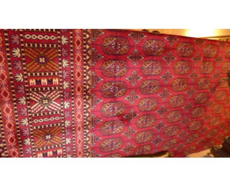 A Bokhara style carpet with red field and gul motifs in a multi border 