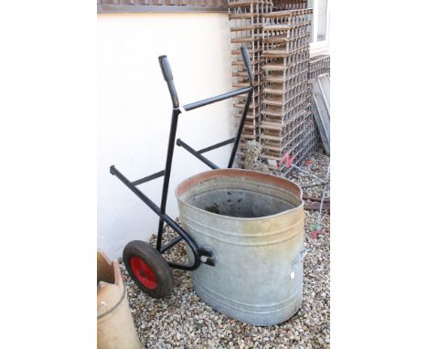 A large galvanised water bowser with rolling frame. 