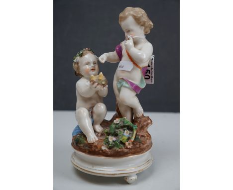 A ceramic figurine of two cherubs with a birds nest, crossed swords mark to base. 