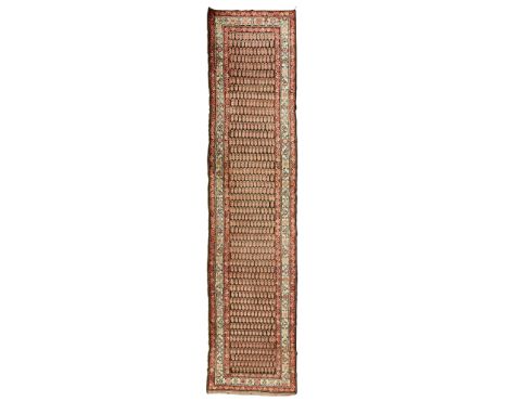 NORTHWEST PERSIAN RUNNER LATE 19TH/EARLY 20TH CENTURY the brown field with allover boteh pattern, within ivory rosette and st