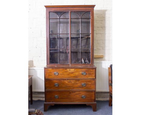 A GEORGIAN MAHOGANY SECRETAIRE CUPBOARD with shaped glazed doors above a secretaire drawer and two long drawers, standing on 