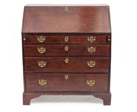 A GEORGIAN OAK BUREAU the fall front opening to reveal drawers and pigeon holes above four long graduated drawers with brass 