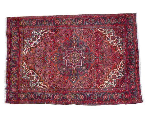 A 20TH CENTURY HERIZ SHERABIN RUG OR SMALL CARPET on a red ground with repeating geometric floral decoration, 294cm x 199cm