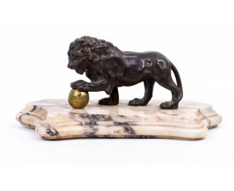 AN ANTIQUE BRONZE LION  with a brass ball standing on a serpentine shaped marble plinth, 27cm x 13cm x 13cm