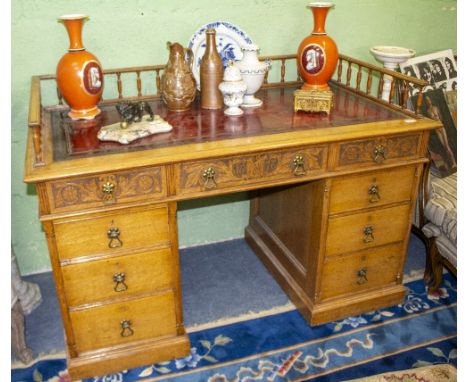 A VICTORIAN OAK PEDESTAL DESKwith a galleried red leather inset top, three drawers with carved decoration and six further dra