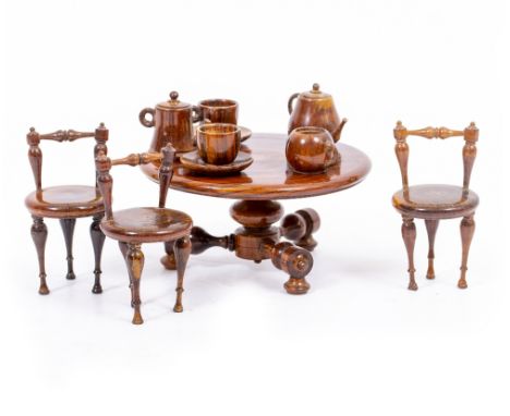 AN ANTIQUE CONTINENTAL TREEN MINIATURE TABLE AND CHAIRS with accessories, the set consists of a circular table, three chairs,