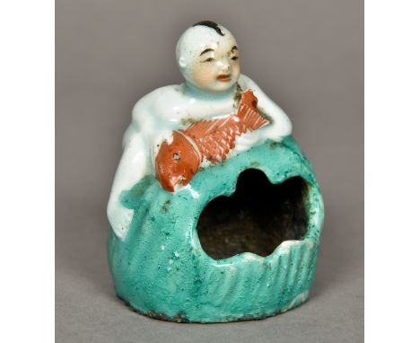 A Chinese porcelain brush washerModelled as a young boy holding a fish, climbing a boulder.  10 cm high. 