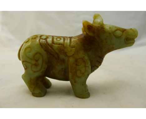 A carved green and russet jade bull with archaistic incised decoration