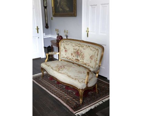 A FRENCH GILTWOOD CANAPÉIN LOUIS XV STYLE, 19TH CENTURYthe back, seat and armrests covered in original Aubusson floral tapest