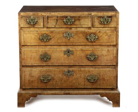 A GEORGE II WALNUT CHESTC.1735the quarter veneered and crossbanded top with a caddy moulded edge, above three short and three