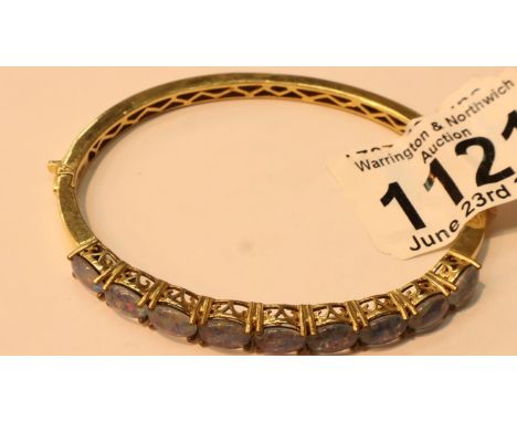 A gold coloured bangle set with nine opal type stones. P&amp;P Group 1 (£14+VAT for the first lot and £1+VAT for subsequent l