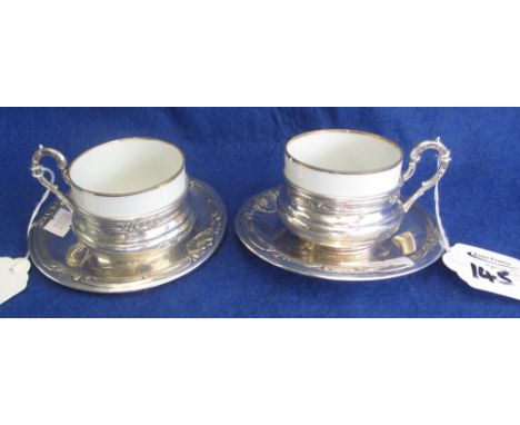 Pair of continental silver coffee cup holders and saucers with porcelain liners.  Hallmarked 800 purity.(B.P. 24% incl. VAT)