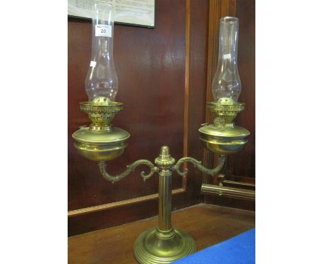Brass double table oil lamp comprising: a pair of double burner lamps with brass reservoirs and clear chimneys, mounted on sc