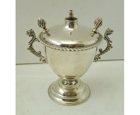 A SILVER PEDESTAL CIGARETTE OIL LAMP LIGHTER of urn form with twin flame finials, central provision for wick, twin cast beast