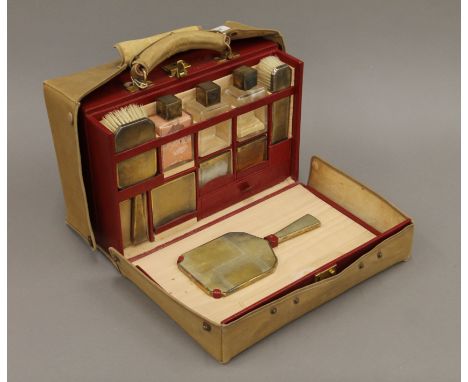 An Asprey & Co travelling vanity case with silver-mounted fitments and outer cover. 34 cm wide.