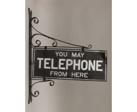 A 'You May Telephone From Here' enamel sign mounted on a wall bracket. The sign 56 cm wide.