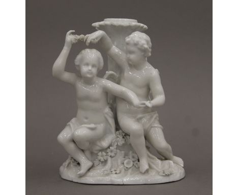 A Meissen blanc de chine porcelain candlestick in the form of a seated cherubs before a tree trunk. 19 cm high.