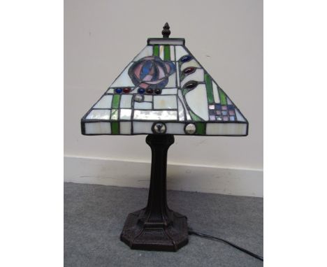 A Tiffany style table lamp with stylised flower and cabouchon stone inlaid on a flared bronzed effect base