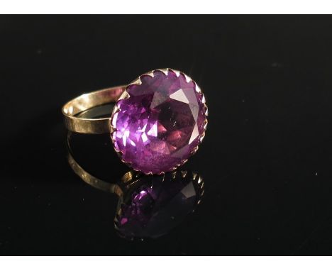 A gold ring set with large round cut amethyst 