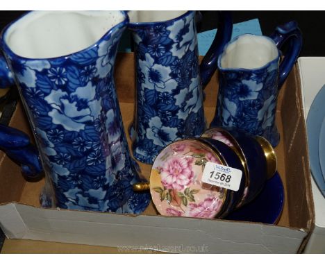 A trio of blue jugs, three Aynsley cups and two saucers; navy blue with pink roses inside the cups.