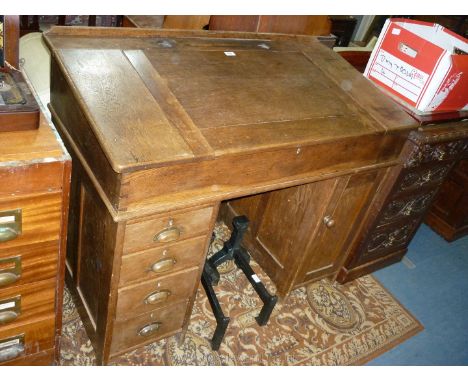 A 19th c. Oak articled clerk's Desk having sloping top, pen trough and two inkwell recesses, the top lifting to reveal a pine