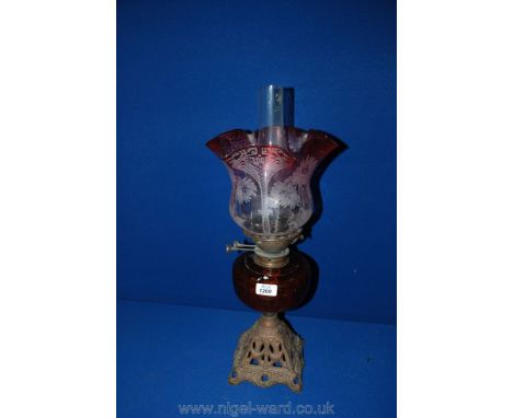 A Victorian glass Oil Lamp with cranberry shade, amber glass reservoir and cast base