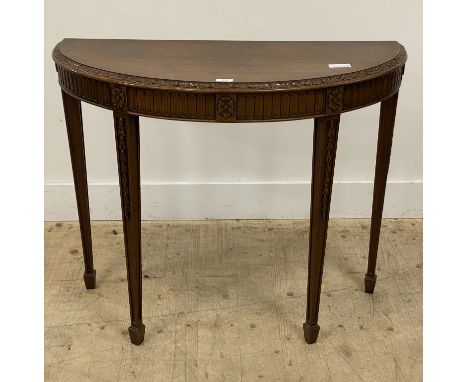 A demi-lune mahogany console table in the Neoclassical taste, early 20th century, floral carved and raised on square tapered 