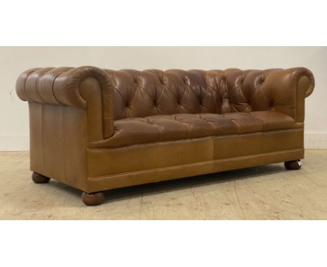 Laura Ashley, A traditional two seat Chesterfield sofa, well upholstered in deep buttoned tan leather, raised on compressed b