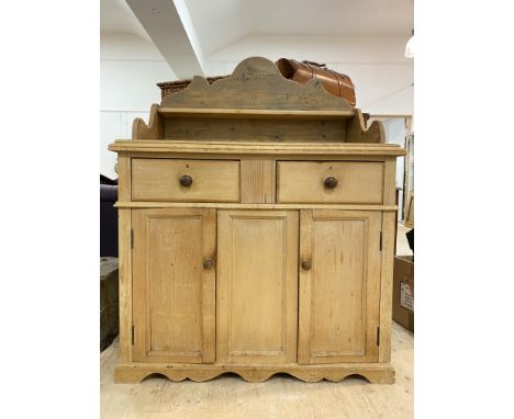 A Victorian style Scotch pine dresser, the shaped back with open shelf above two drawers and two panelled cupboards, raised o