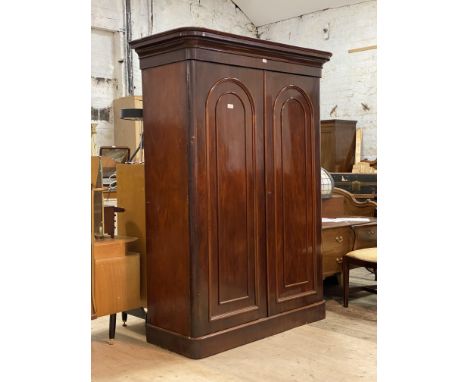 A Victorian mahogany double wardrobe, the projecting cornice over two arch panelled doors enclosing a combination of slides, 