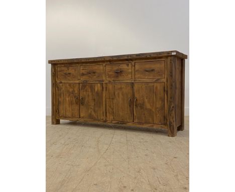 A stained hardwood sideboard, fitted with four drawers over two double cupboards enclosing a shelf, raised on stile supports.