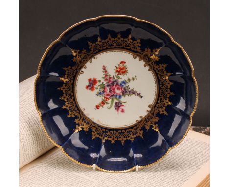 A Worcester lobed dish, painted with a vignette of colourful flowers within scrolling gilt foliage, reserved on a wet blue gr