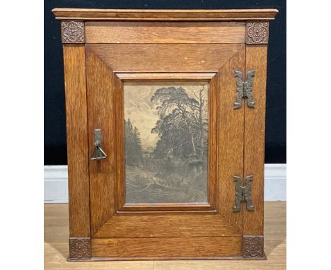 An Arts &amp; Crafts oak wall cabinet, the door set with a glazed lithographic landscape print and enclosing a shelf, bearing