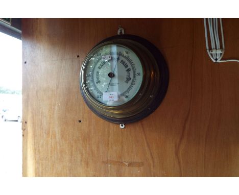 A John Barker & Co Ltd of Kensington brass cased ship's barometer having white dial, mounted on an oak circular board