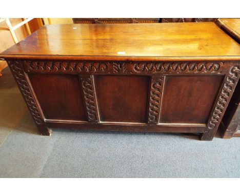 An 18thC oak coffer the two plank top over three panelled front elevation having carved surround 