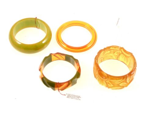 Two "apple juice" lucite bangles, a 35mm wide carved floral design bangle, internal diameter 62mm, an 18mm green and apple ju